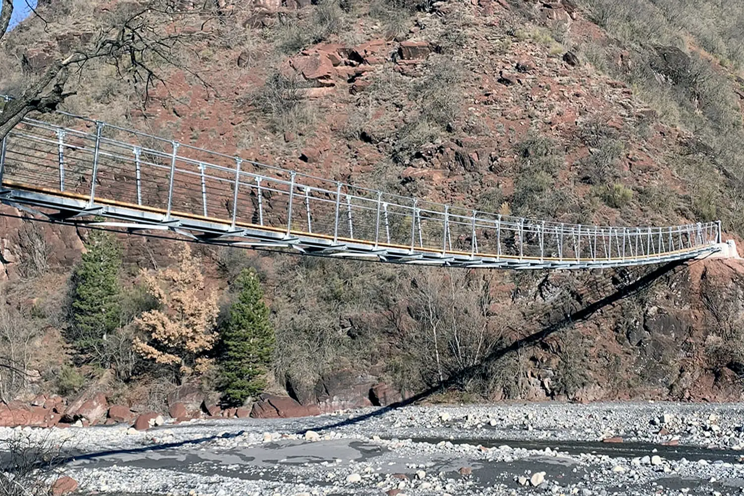 Passerelle suspendue souple avec platelage suivant la flèche de l’ouvrage